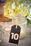 Rustic Table Numbers - Michelle and Jason used Rustic wood tags tied with twine on Mason jars for table numbers that we filled with sand and a votive .
